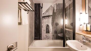 A bathroom with a bathtub, a sink, a mirror, and a towel rack.