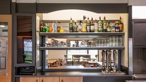 Zona de bar con estanterías llenas de botellas de licor y vasos.