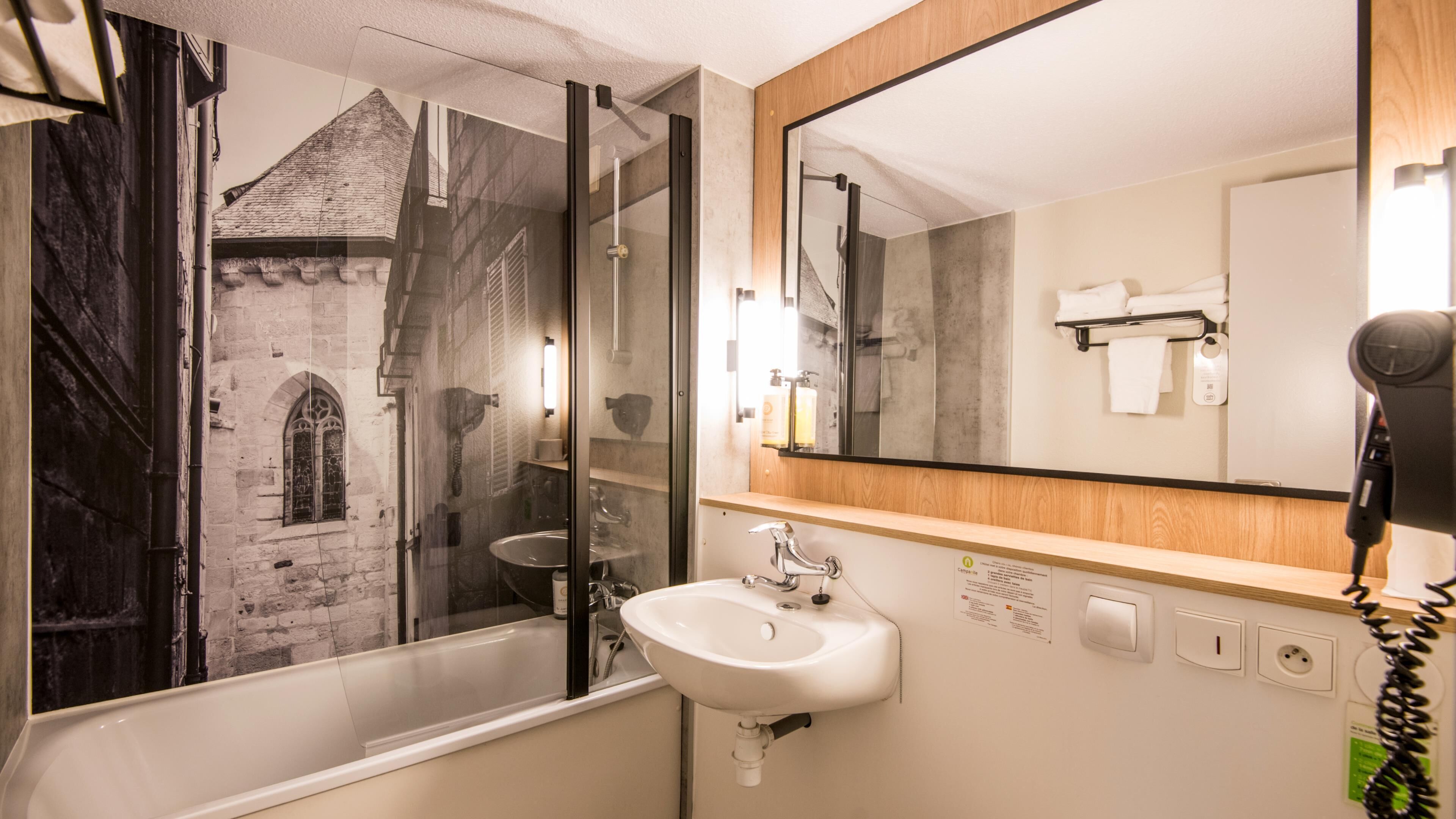 A bathroom with a glass-enclosed shower, a sink, a mirror, and a hairdryer.