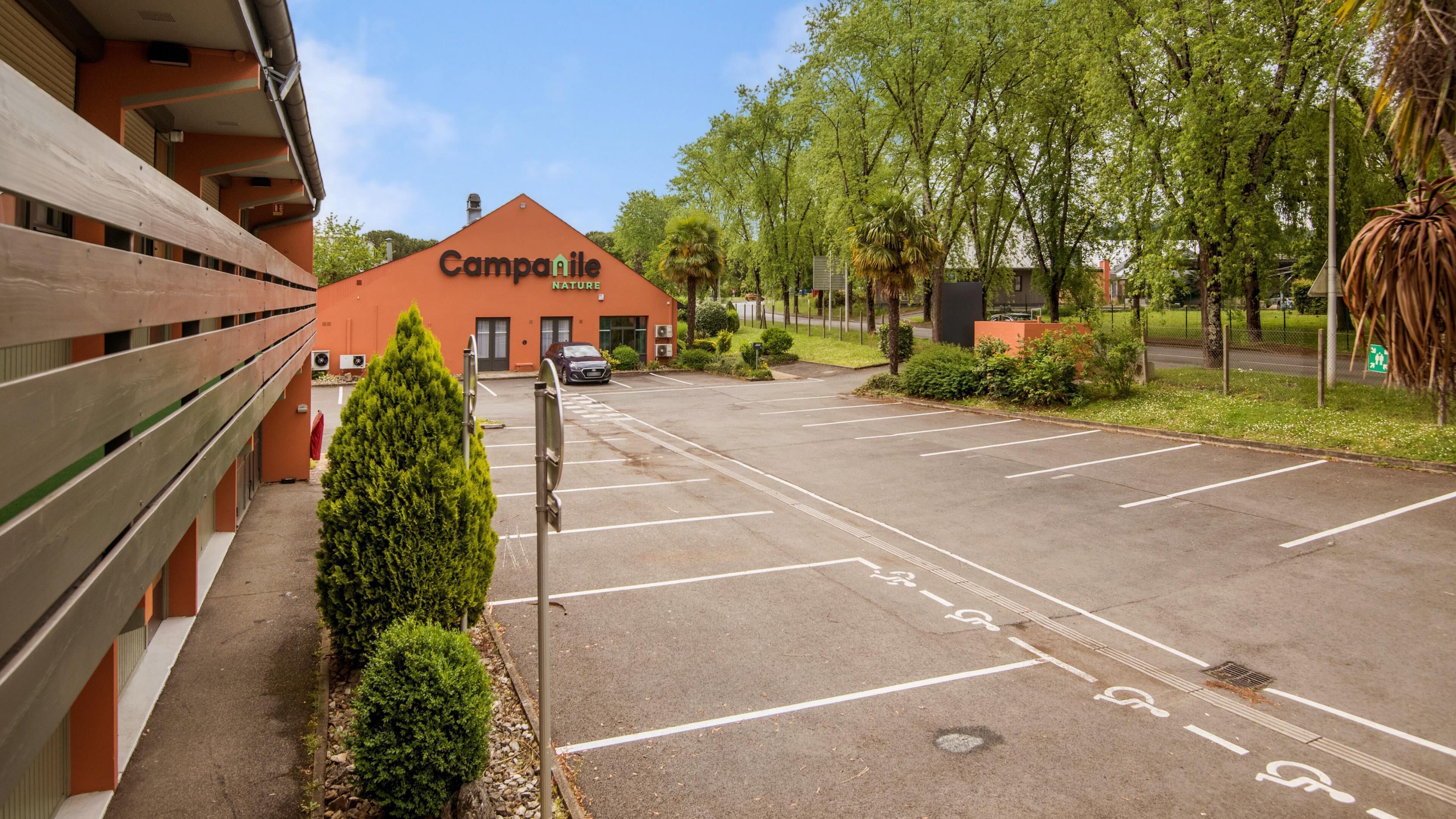 A parking lot with a building labeled 'Campanile Nature' and a row of trees.