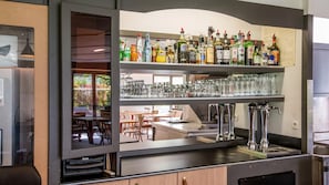 Un espace bar avec des étagères remplies de bouteilles d’alcool, des verres et un comptoir doté de robinets.