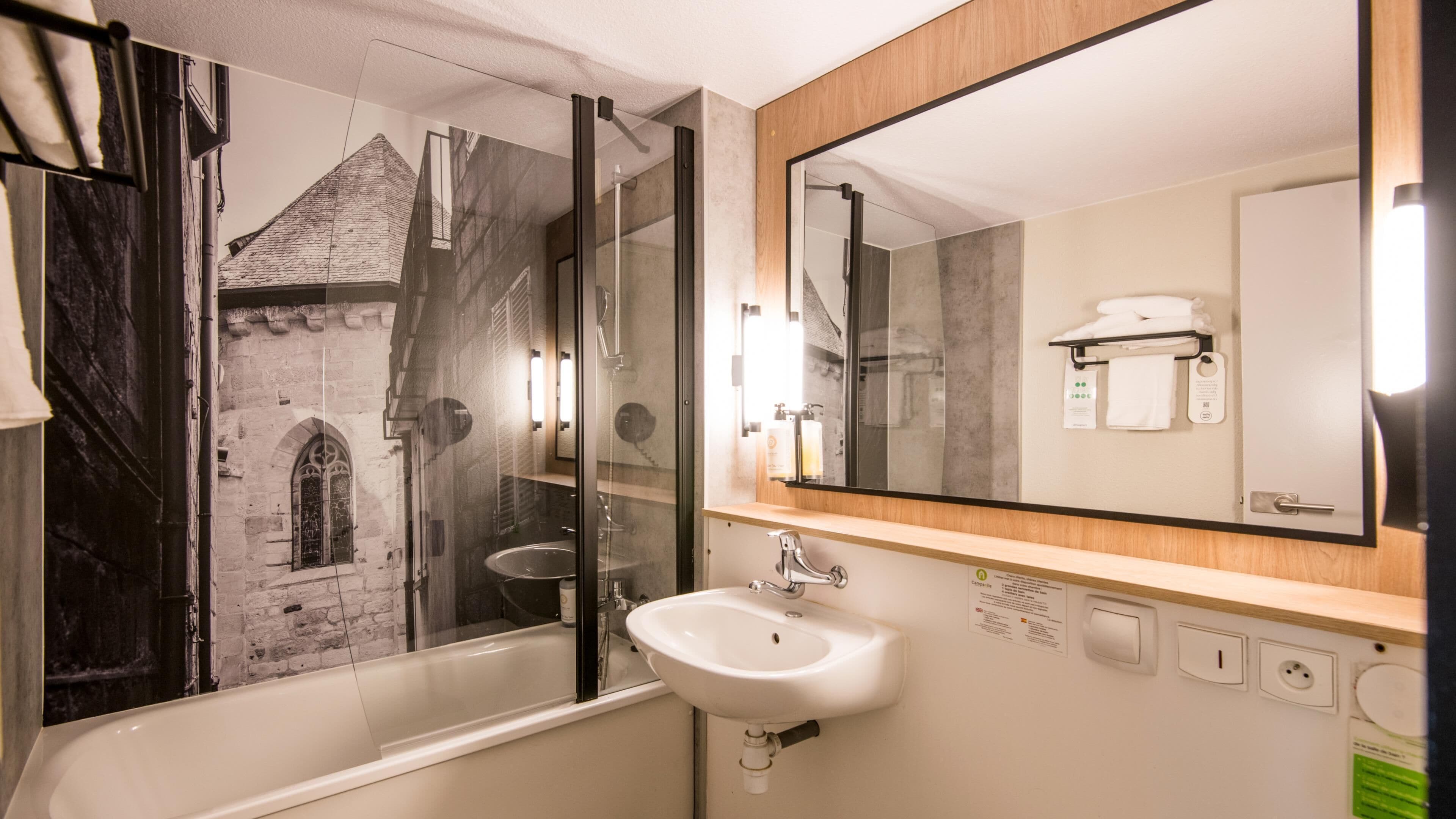 A modern bathroom with a bathtub, a sink, a large mirror, and a shower with a glass door.