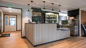 A modern kitchen with a central island, pendant lighting, and a brick accent wall.