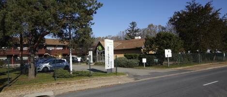 A road with a sign for Campina, a fenced area with trees, and a building with a red roof.