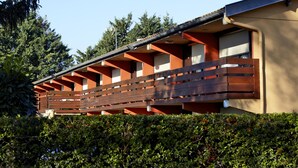 A row of cabins with wooden balconies, surrounded by dense greenery.