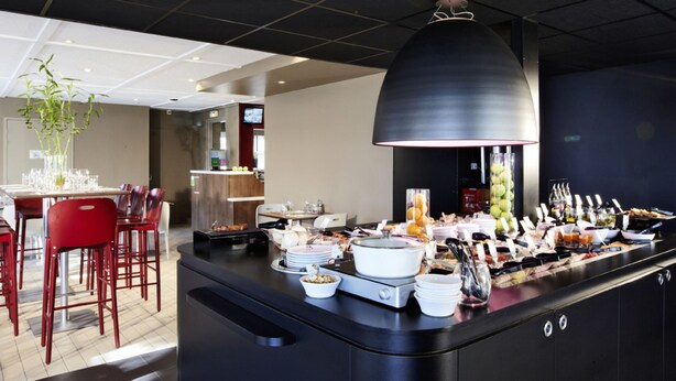 A buffet setup with various food items and a dining area with red chairs and a table.