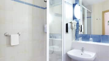 A bathroom with a glass-enclosed shower, a white sink, and a mirror with a blue-tiled backsplash.