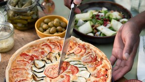 A pizza with various toppings being cut.