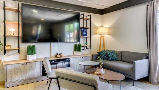 Ein modernes Wohnzimmer mit Flachbildfernseher, einer Couch, einem Couchtisch und einer TV-Bank mit Regalen.