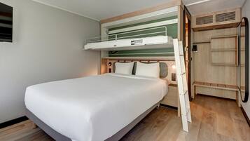 Un lit superposé avec un lit inférieur, une tête de lit en bois et une table de chevet avec une lampe.