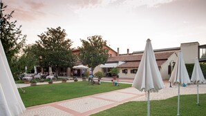 Un patio con mesas al aire libre, sombrillas y un sendero pavimentado.