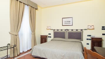 A neatly arranged bedroom with a bed, a bedside table, a chair, and a small table.