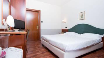 Una habitación de hotel con un escritorio de madera, una cama, una silla y una mesita de noche.