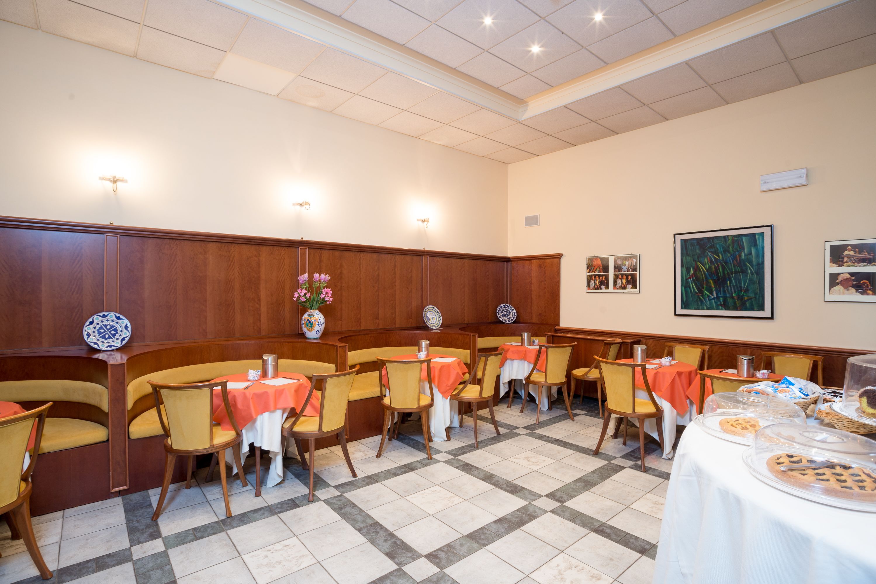 Un comedor con paneles de madera, sillas amarillas y mesas con manteles blancos.