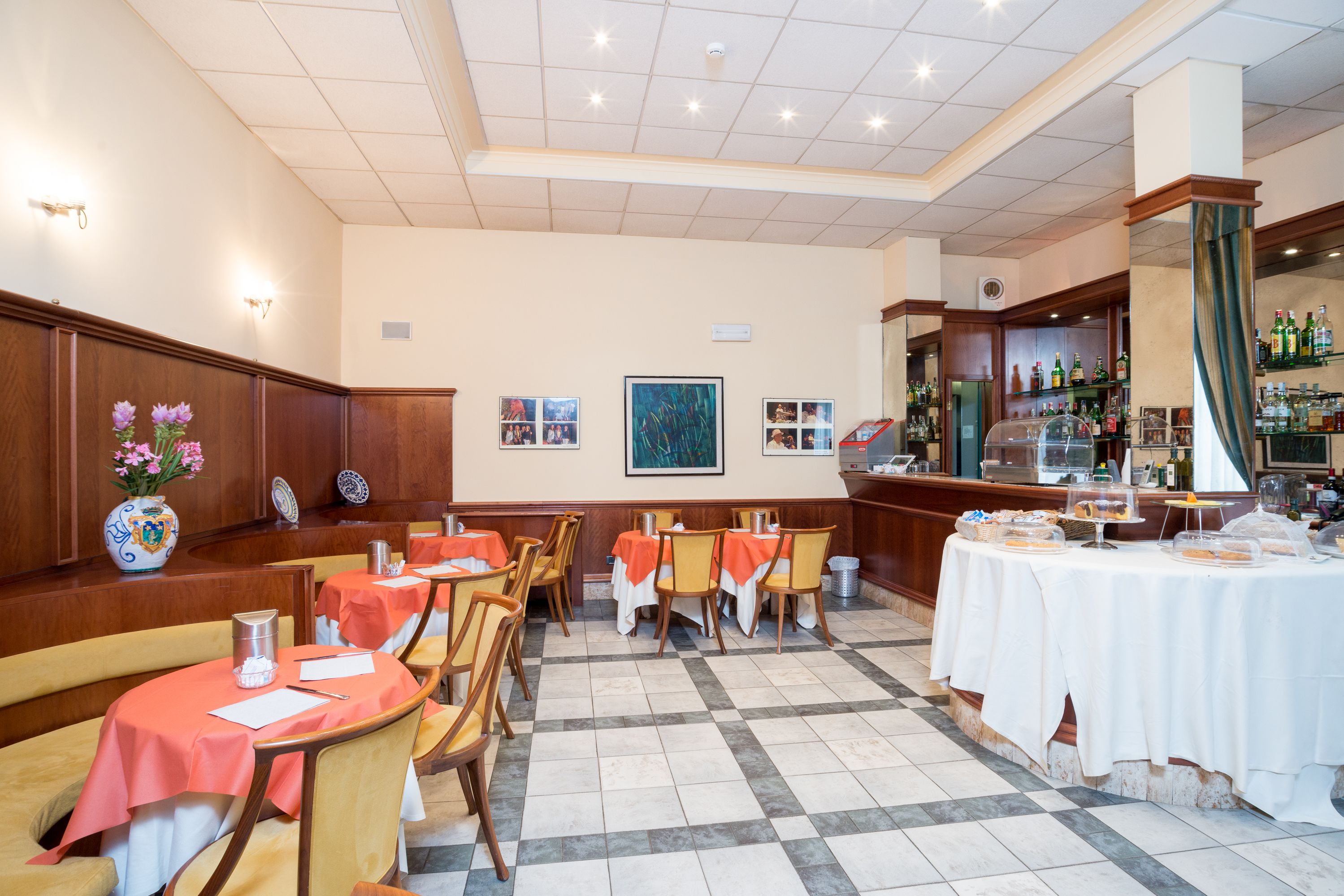 A restaurant with round tables, chairs, and a bar area.