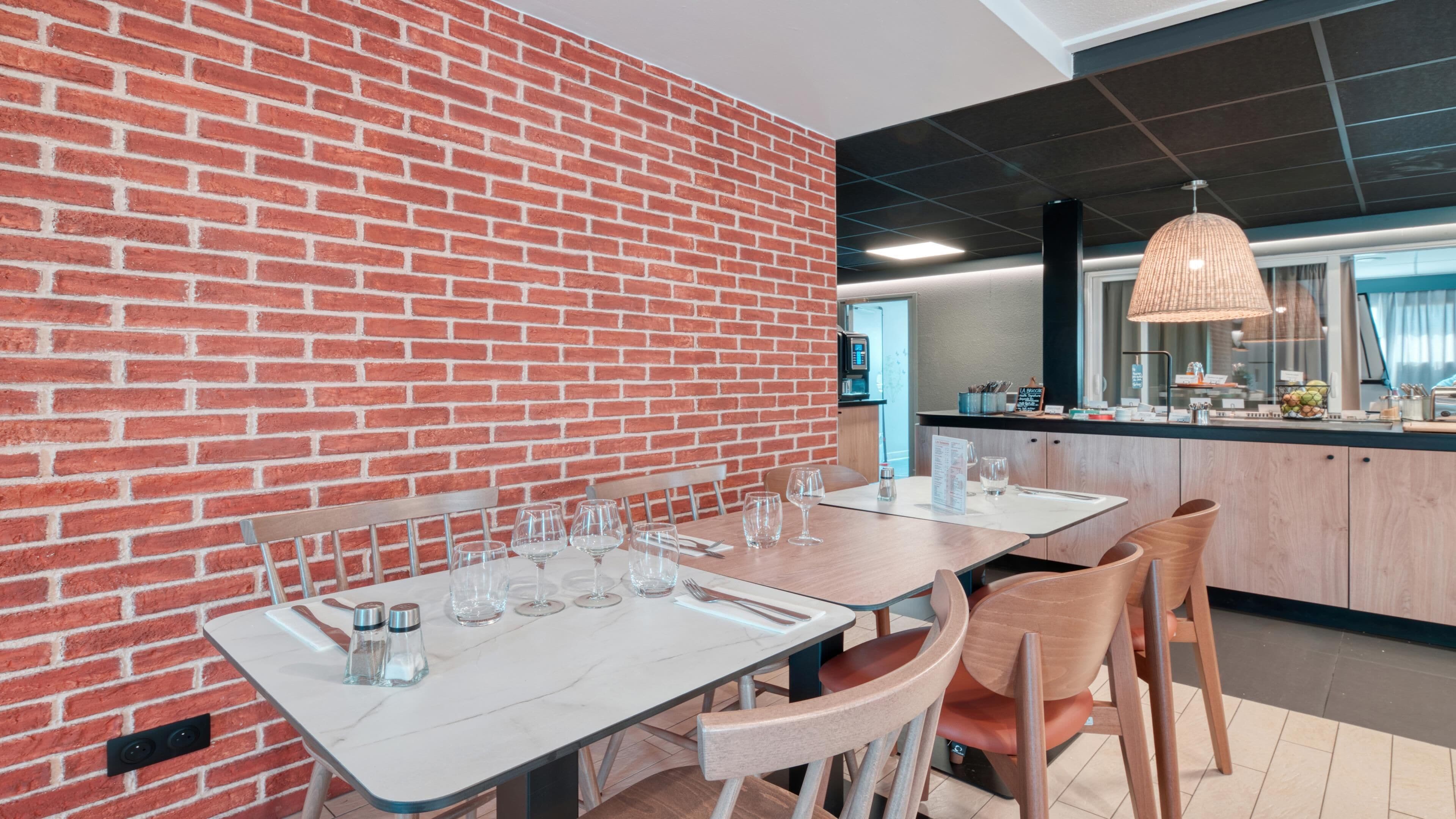 Un comedor con paredes de ladrillo, una mesa de mármol y sillas de madera.