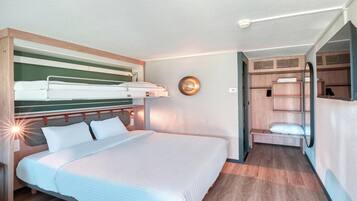 Quarto de hotel com beliche, mesa de cabeceira, espelho e guarda-roupa.