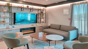 Una sala de estar moderna con una televisión de pantalla plana, una chimenea, un sofá y dos sillones.