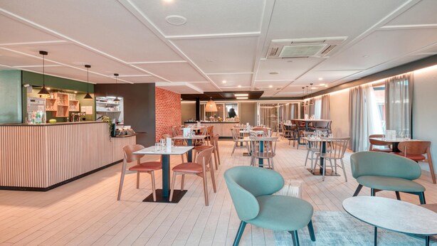Un restaurante moderno con zona de bar, suelo de madera y una variedad de arreglos de asientos, incluyendo mesas y sillas.