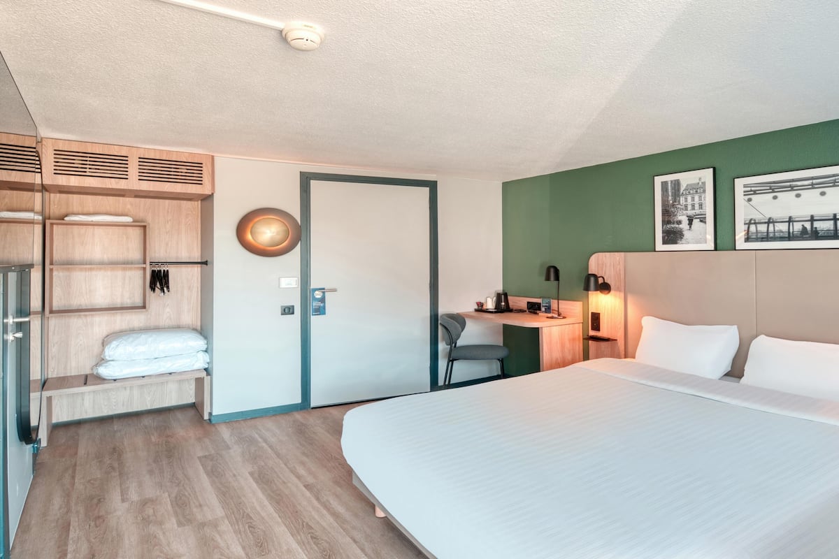 Une chambre d’hôtel avec un grand lit, un bureau avec une chaise, une armoire et un espace douche.