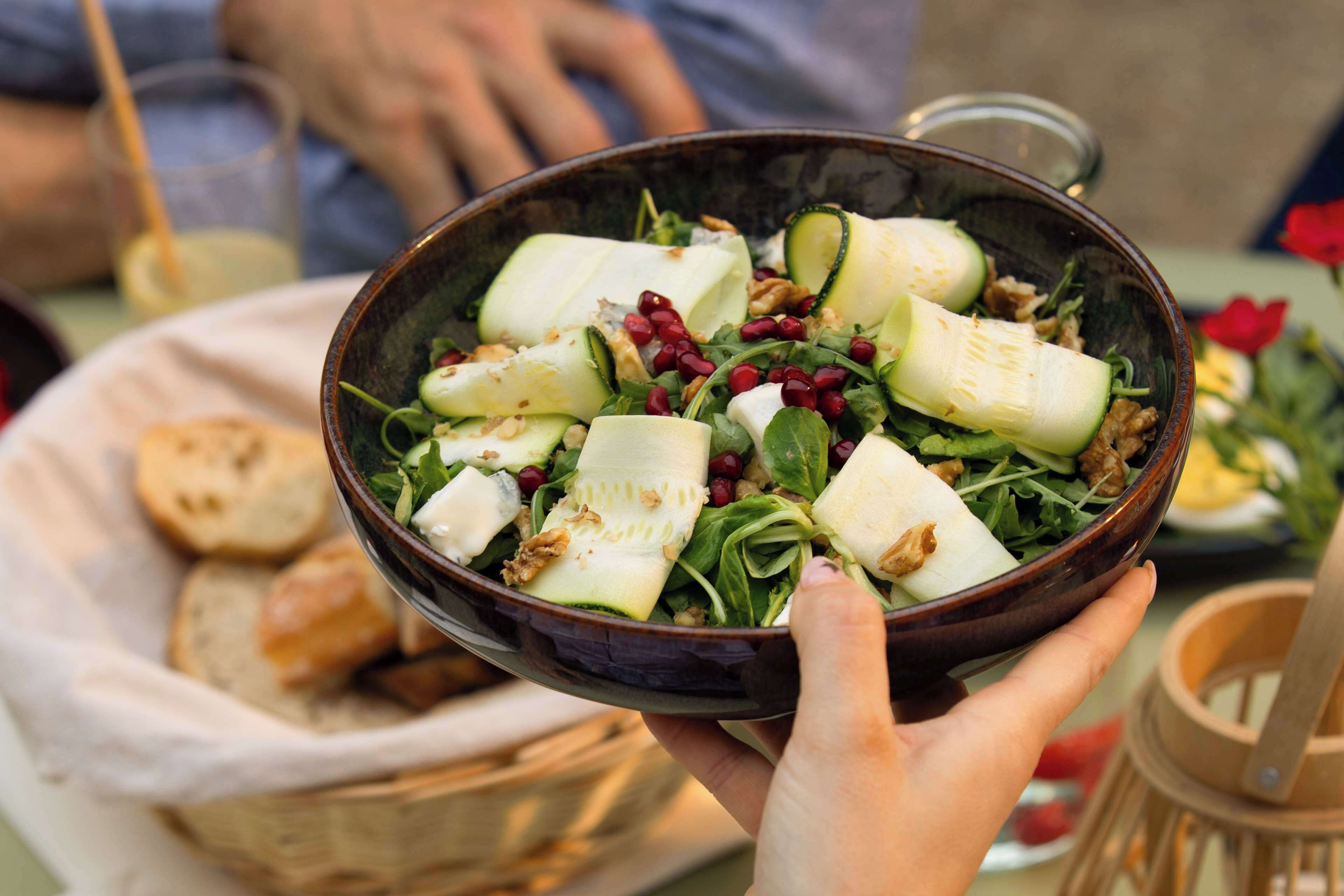 Eine Salatschüssel mit Gurken, Pomegranate-Kernen und Blattsalat.