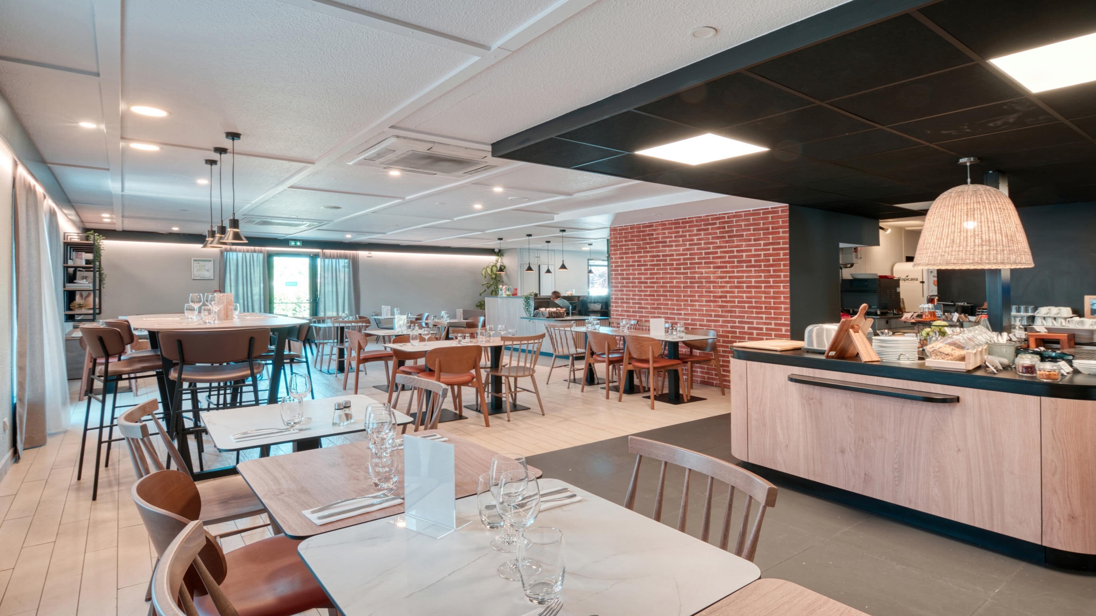 Un restaurante moderno con mobiliario de madera y metal, una pared de acento de ladrillo y una barra con diferentes tipos de comida.