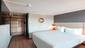 Una habitación de hotel con una cama grande, un armario, una lámpara de pared y una lámpara en el techo.