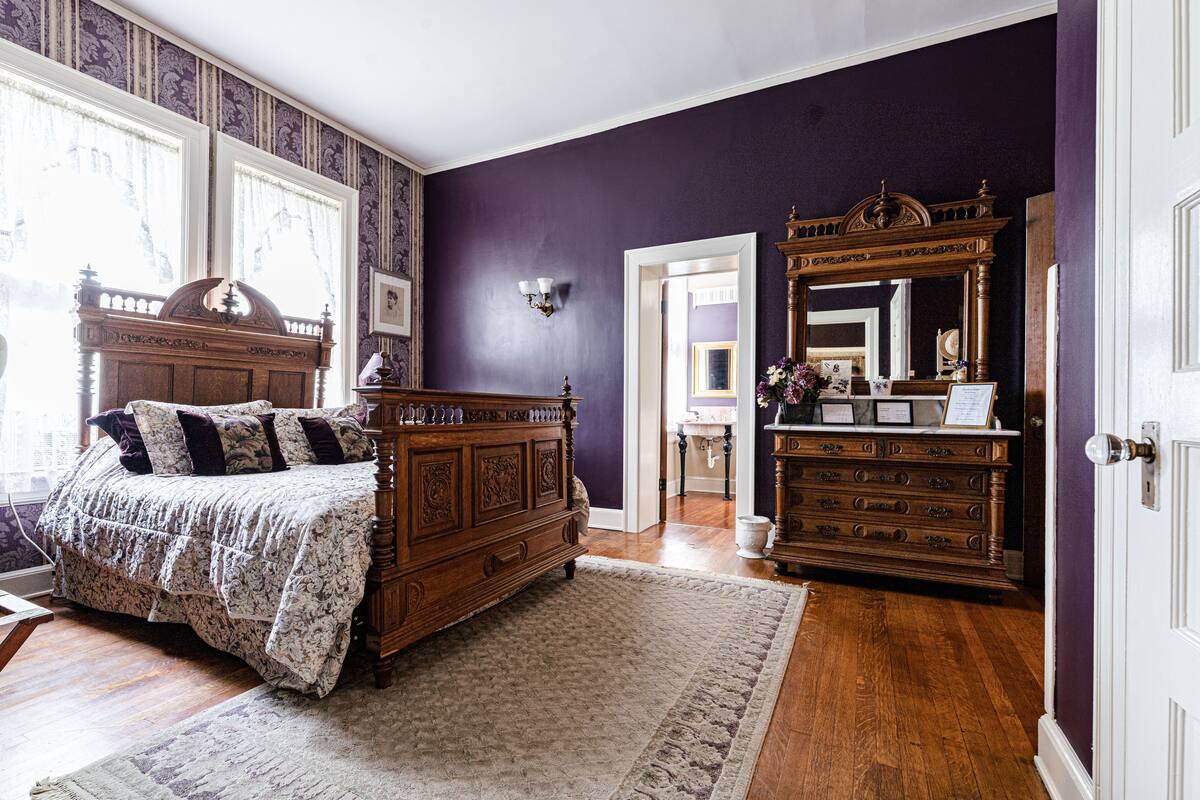 A bedroom with a large bed, a dresser, and a mirror.