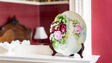 A decorative plate with floral designs on a white mantelpiece.