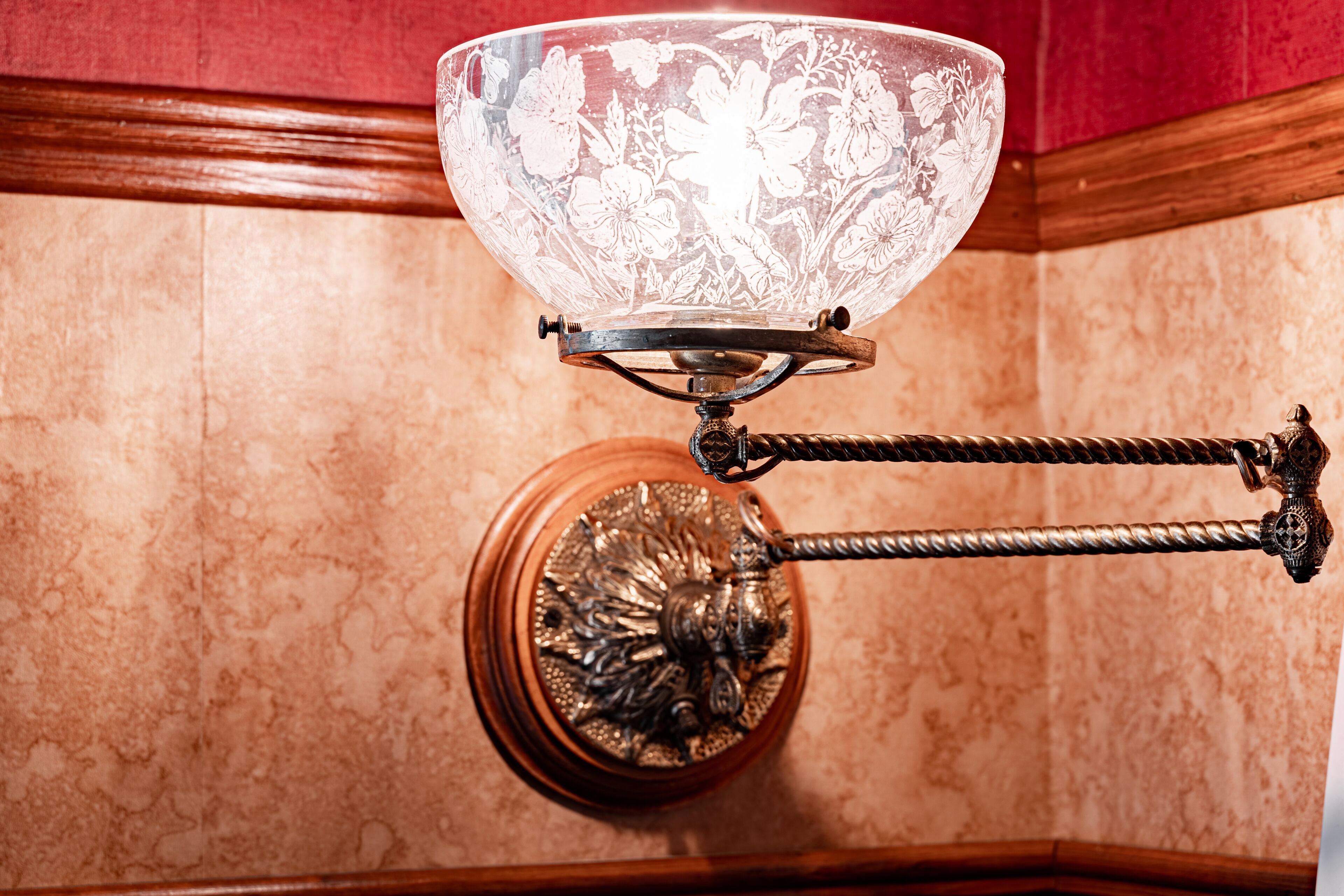 A chandelier with a floral design, a decorative base, and a wooden frame.