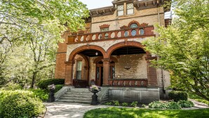 A historic brick building with arched entryways and a prominent front porch. - Vrooman Mansion B&B (Bloomington)