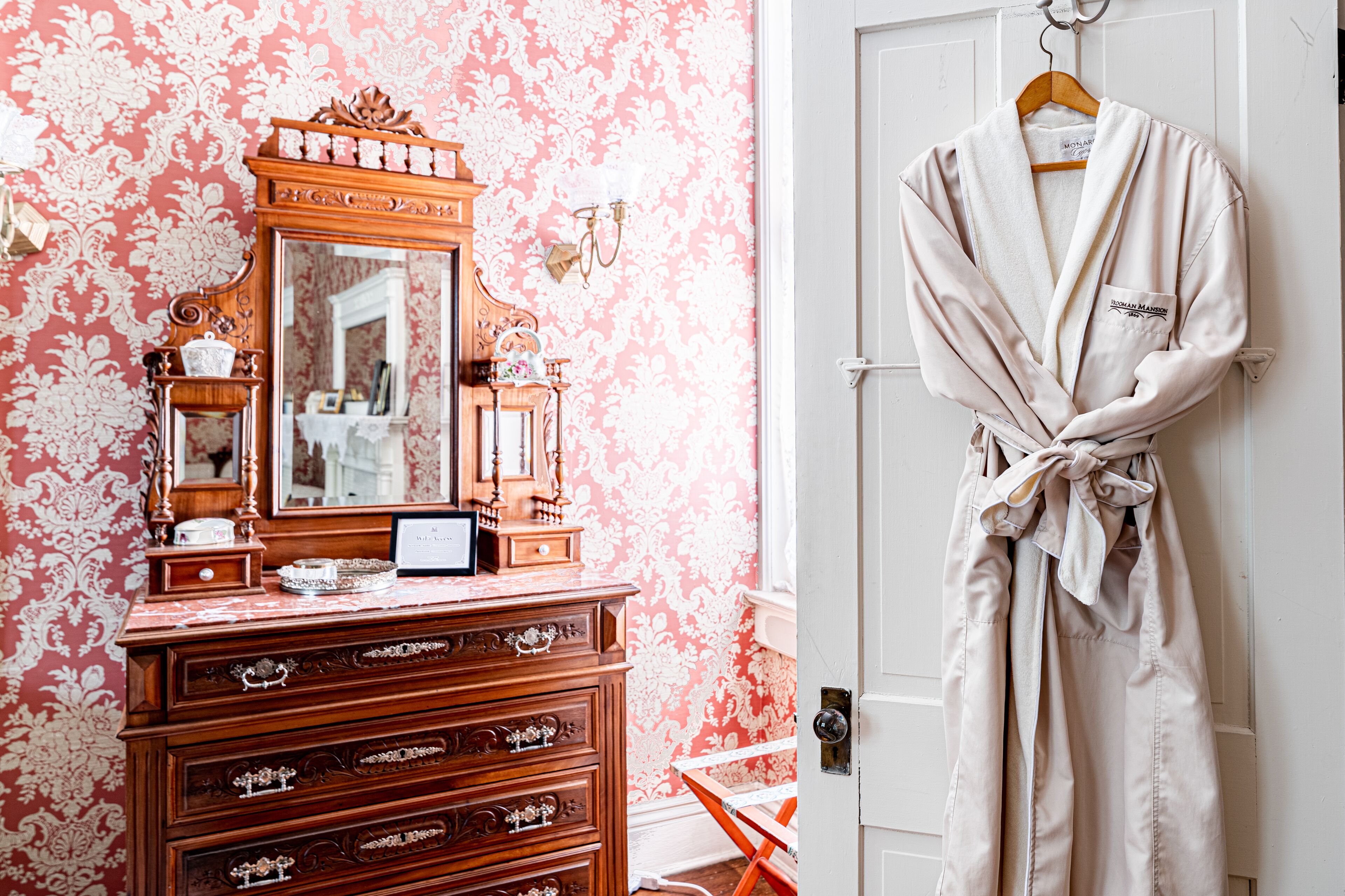 A room with a wooden dresser, a mirror, and a robe hanging on a door.