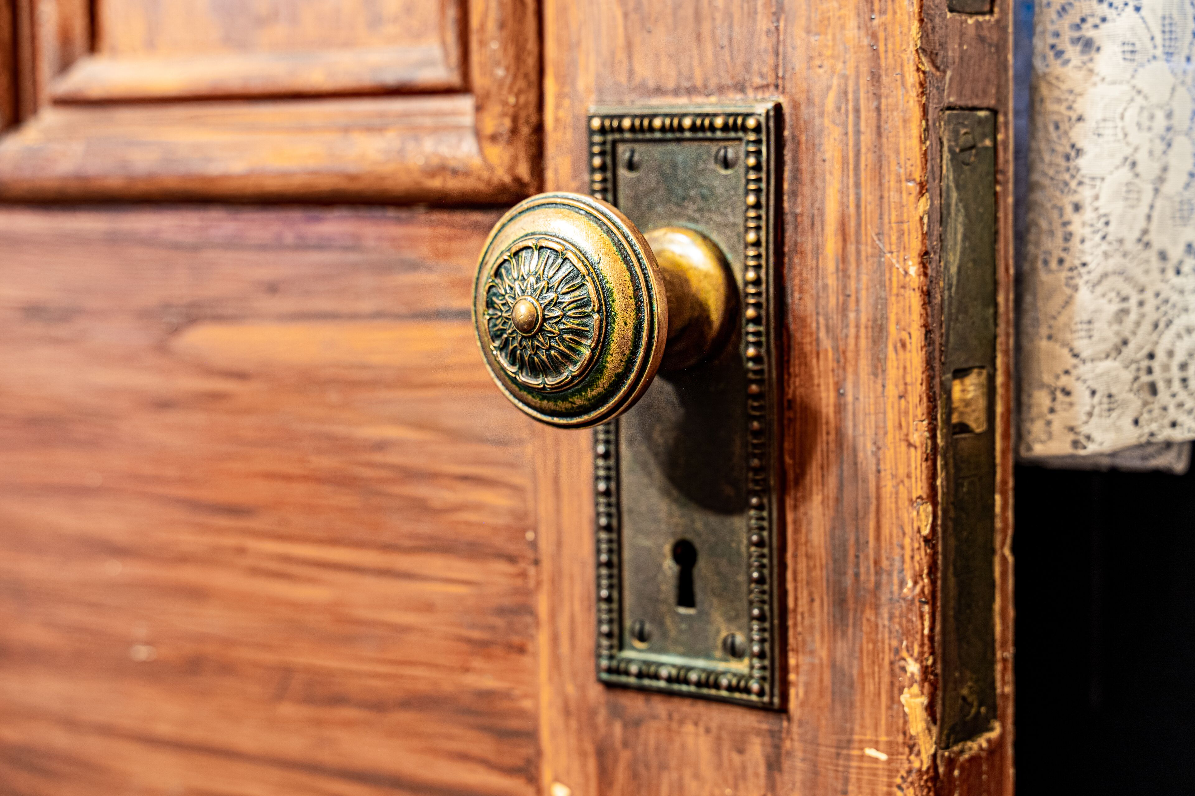 A wooden door with a brass doorbell and a keyhole.