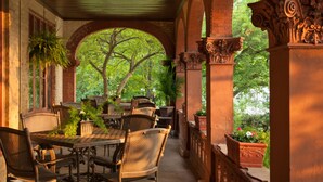 A covered patio with a brick archway, wicker furniture, and potted plants. - Vrooman Mansion B&B (Bloomington)