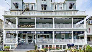 A two-story building with a sign reading "Lillagård Bed and Breakfast." It features a balcony on the second floor and a front entrance with steps. - The Lillagaard B&B (Ocean Grove)