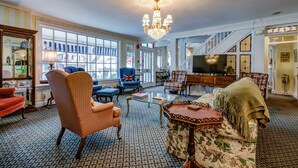 A spacious living room with a chandelier, a blue armchair with a Union Jack flag, a floral sofa, and a television. - The Lillagaard B&B (Ocean Grove)