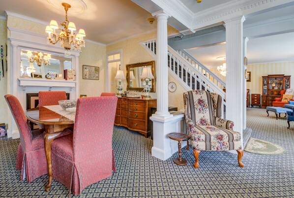 A spacious dining area with a wooden table, red patterned chairs, and a chandelier. - The Lillagaard B&B (Ocean Grove)