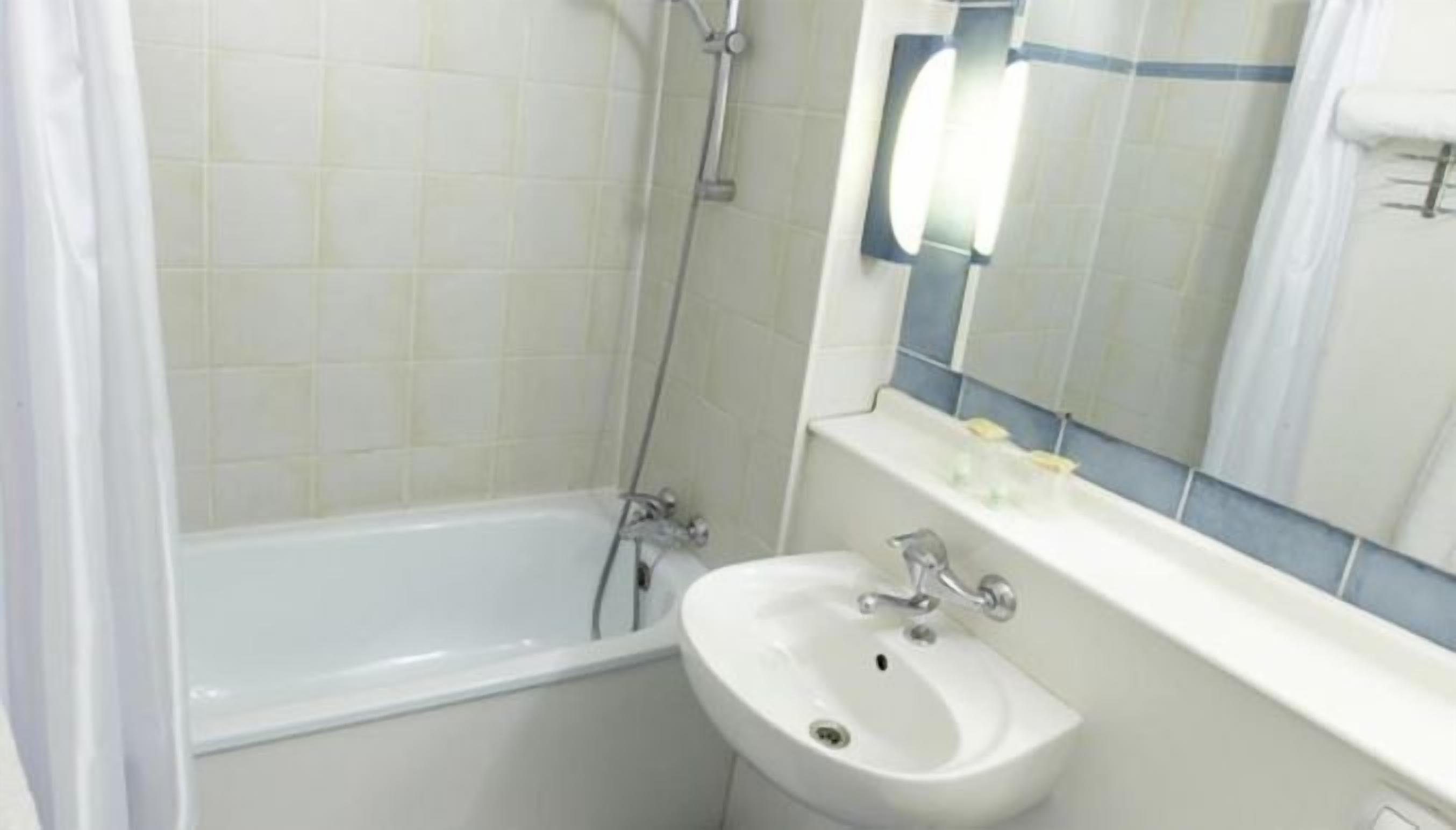Un baño con bañera, lavamanos y espejo.