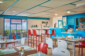 Een restaurant met tafels, stoelen, een toonbank en planken met spullen.