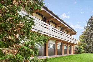 Een modern meerlaags gebouw met balkons, grote ramen en een verzorgd gazon.