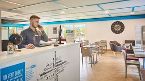 A reception desk with a globe, a clock, and multilingual welcome signs. - Kyriad Direct Epinal (Epinal)