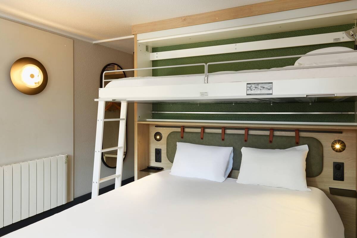 A bunk bed with a ladder, a headboard with storage compartments, and a wall-mounted light fixture.