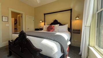 A double bed with a dark headboard, a bedside table with a lamp, and a window with curtains.