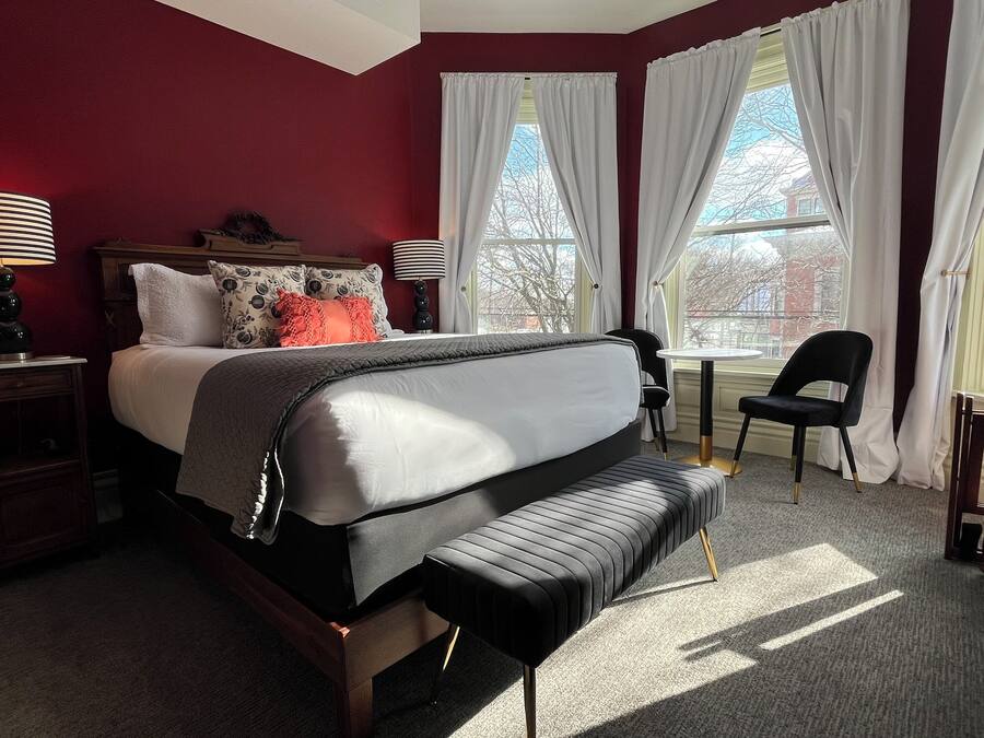 A neatly arranged bedroom with a bed, bedside tables, a chair, and a small table.