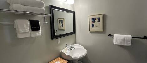 A bathroom with a sink, mirror, towel rack, and a small wooden table.