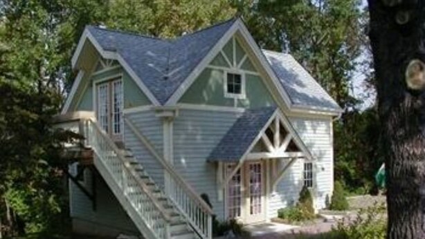 A small, single-story house with a steeply pitched roof, a front porch, and a staircase leading to the entrance. - Alpine Haus Bed & Breakfast Inn (Vernon)