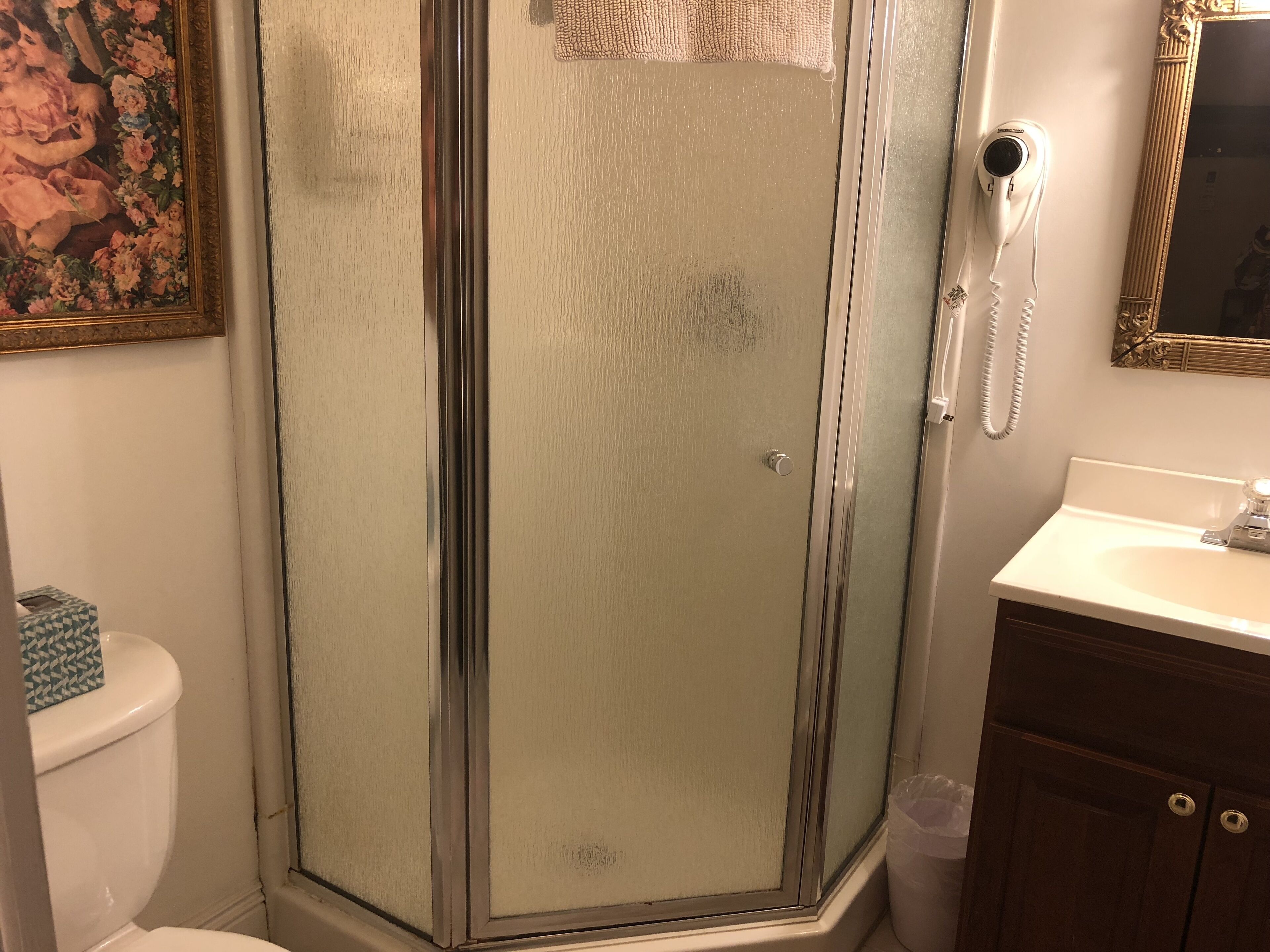 A bathroom with a glass-enclosed shower, a toilet, a sink, and a telephone.