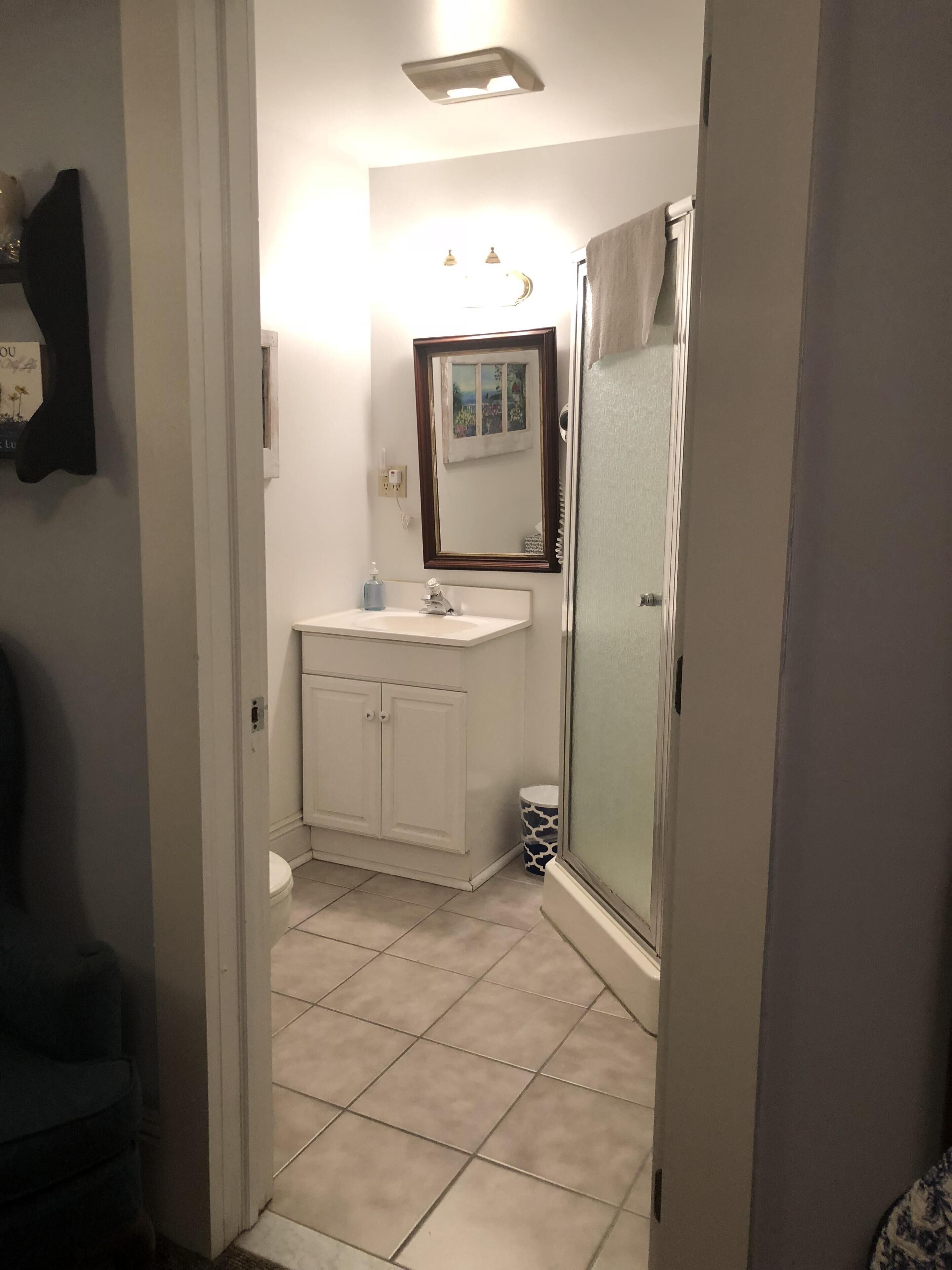 A bathroom with a white sink, mirror, and toilet, and a shower area with a glass door.