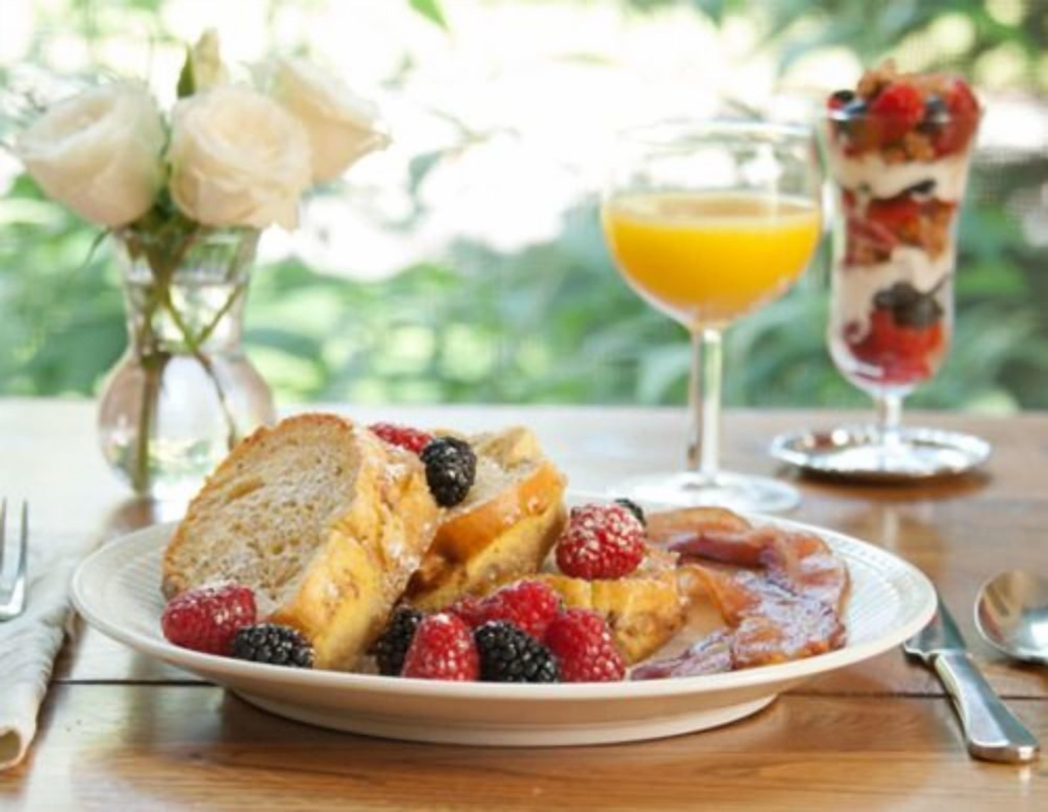 A breakfast setting with a plate of toast, berries, and a glass of orange juice.