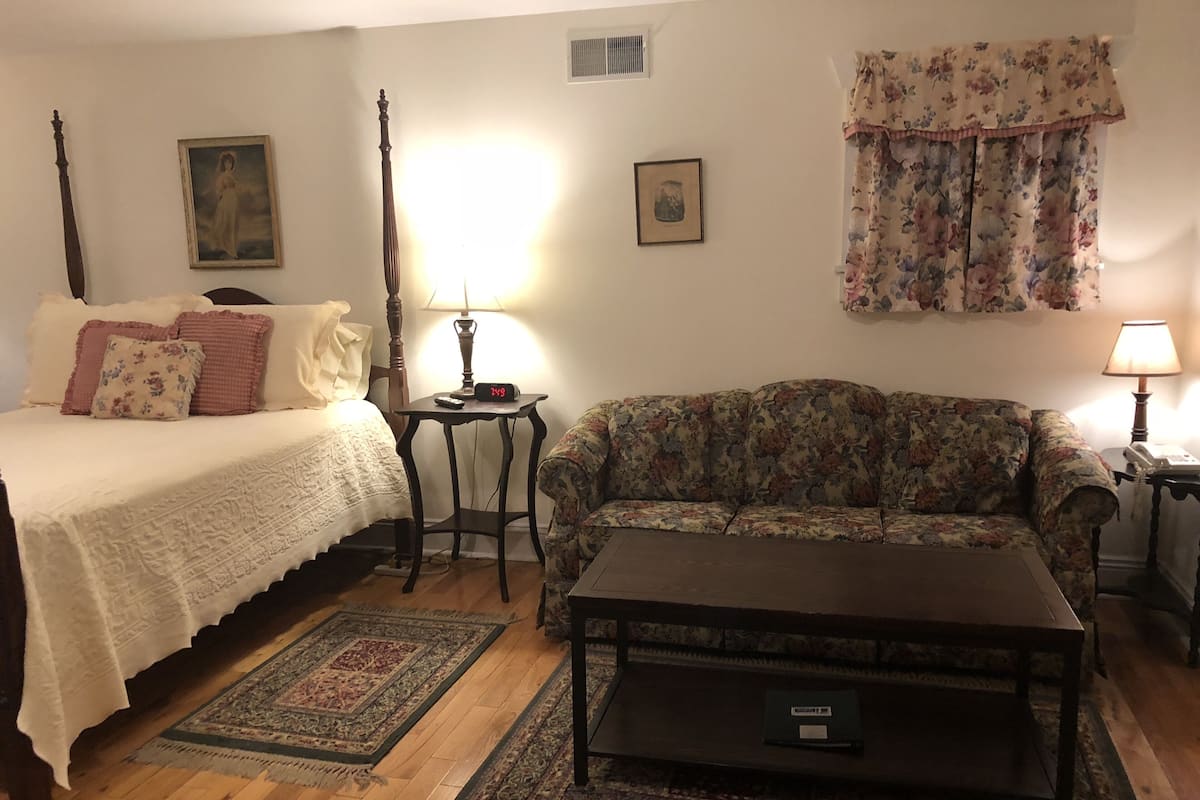 A cozy room with a bed, a sofa, a small table, and a lamp.